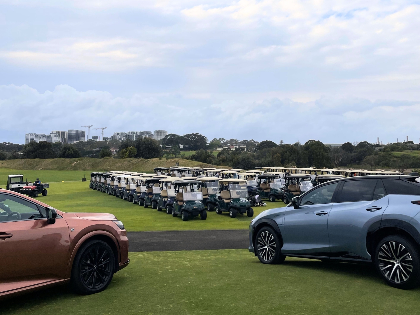 Fleet of golf carts and Lexus vehicles on golf course.