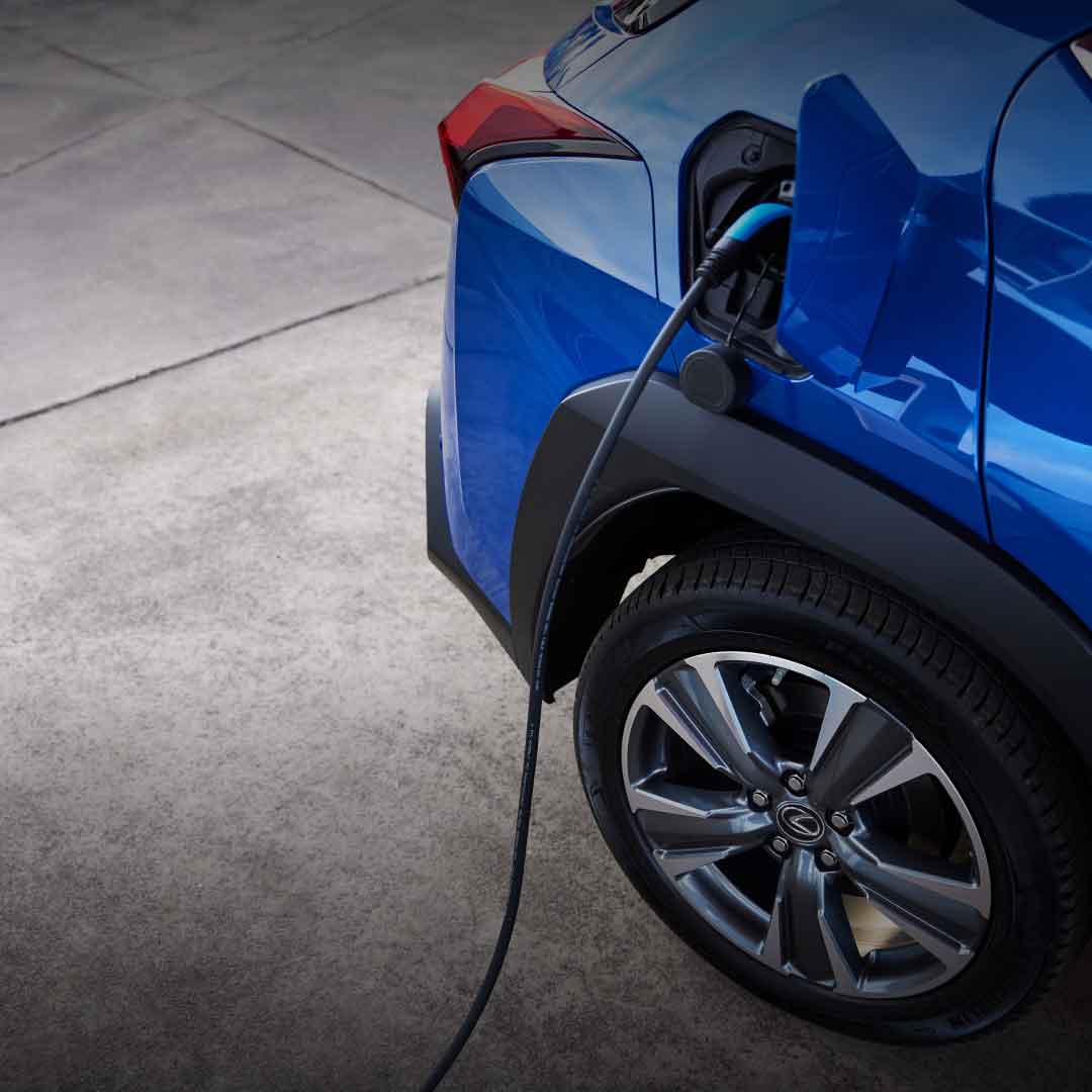 A blue UX 300e sits charging on grey pavement
