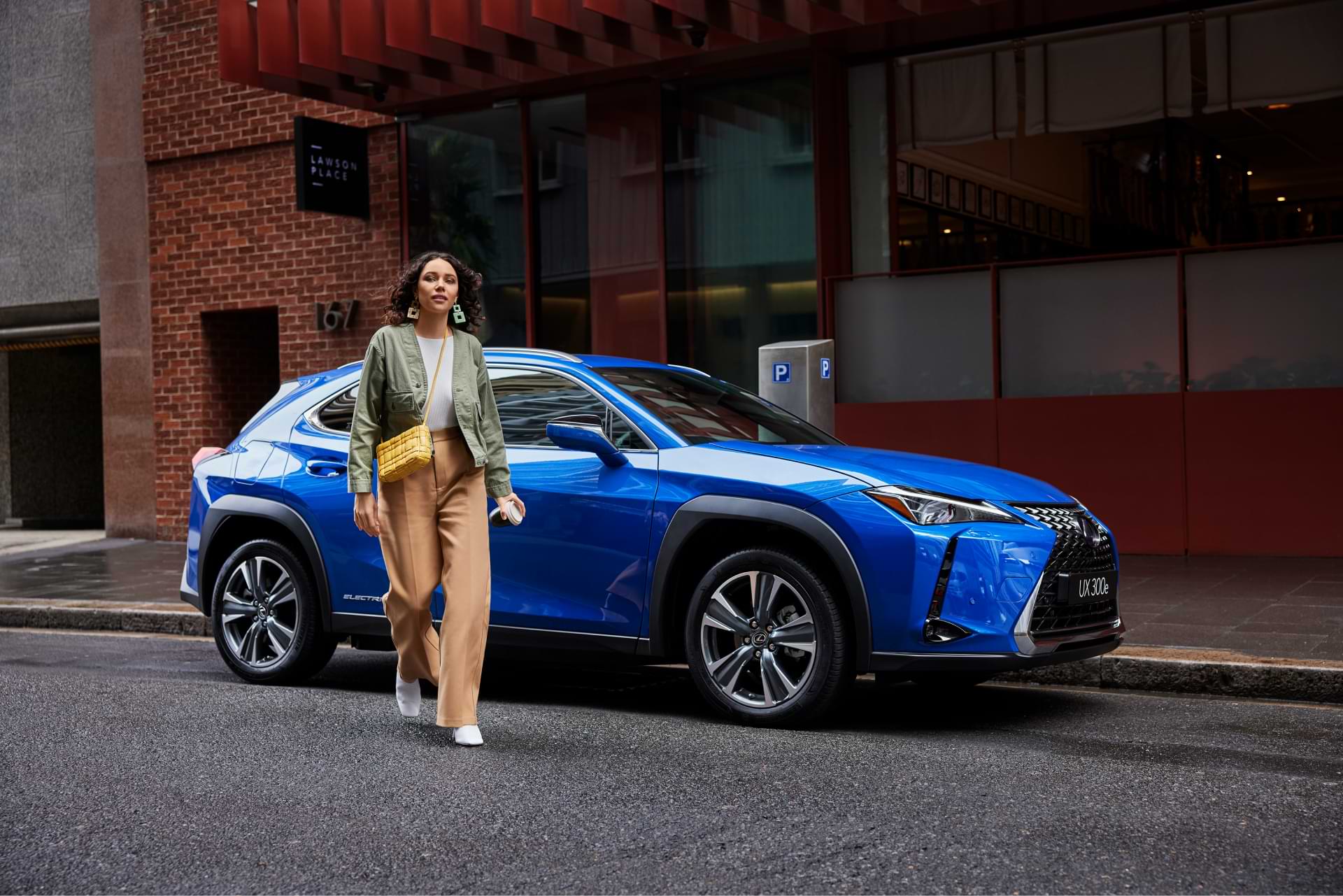 A lady walks away from a parked, blue UX 300e.