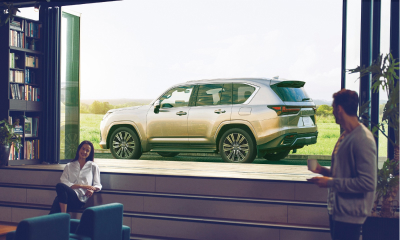 Two people sitting inside with a Lexus parked in the background